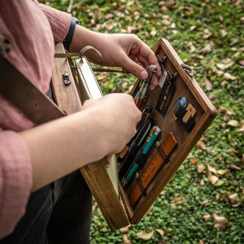 Caixa de madeira para artistas com design vintage e compartimentos organizadores.
Bolsa tiracolo de madeira com detalhes elegantes em couro e trava de latão.