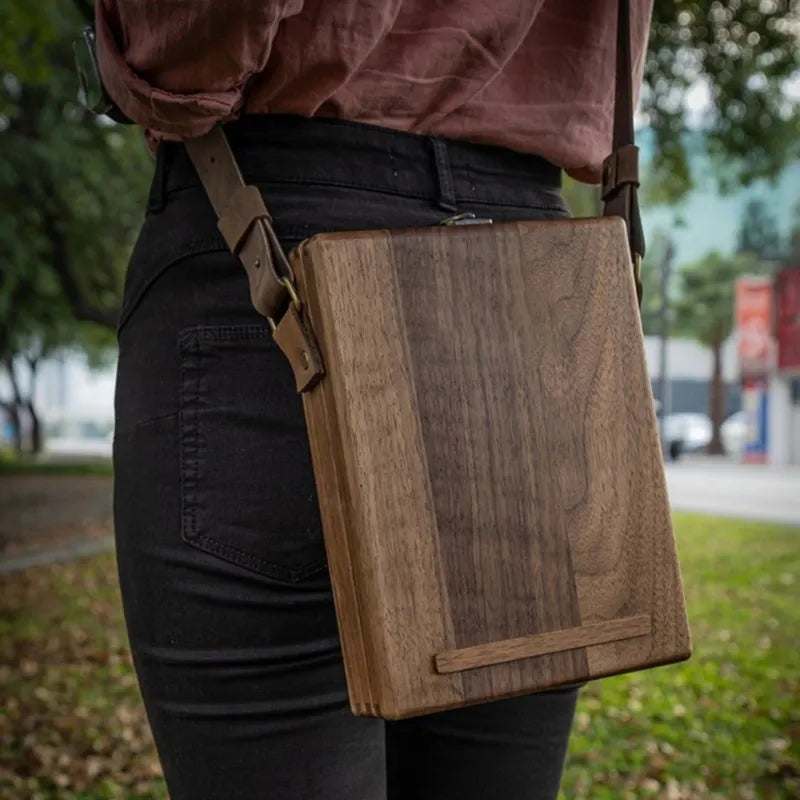 Caixa de madeira para artistas com design vintage e compartimentos organizadores.
Bolsa tiracolo de madeira com detalhes elegantes em couro e trava de latão.