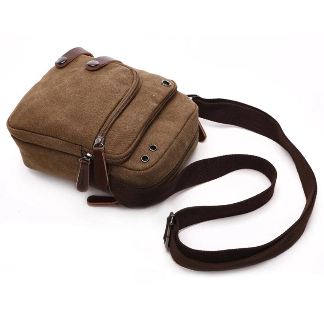 Bolsa de Ombro Masculina, confeccionada em lona resistente, sendo versátil para diversas ocasiões. Seu interior possui vários bolsos, incluindo um específico para celular, além de um espaçoso compartimento com fechamento em zíper. Com um estilo vintage, essa bolsa é perfeita para aqueles que buscam praticidade e estilo.