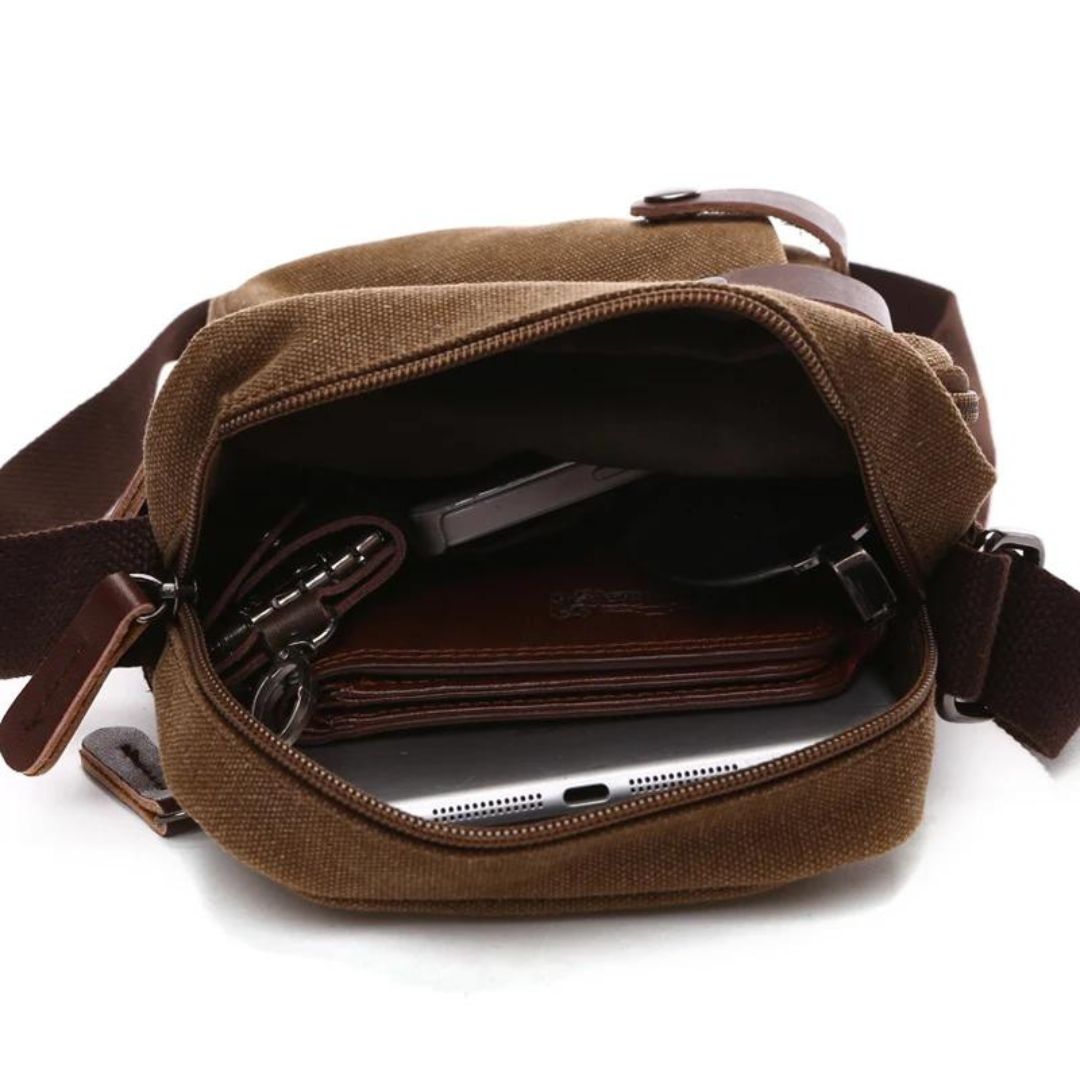 Bolsa de Ombro Masculina, confeccionada em lona resistente, sendo versátil para diversas ocasiões. Seu interior possui vários bolsos, incluindo um específico para celular, além de um espaçoso compartimento com fechamento em zíper. Com um estilo vintage, essa bolsa é perfeita para aqueles que buscam praticidade e estilo.